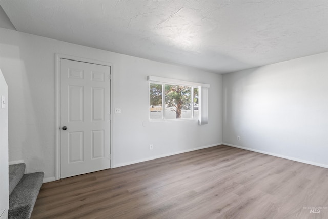 unfurnished room with stairs, baseboards, and wood finished floors