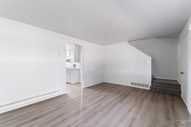 unfurnished living room featuring a baseboard heating unit, visible vents, light wood-style flooring, and stairs