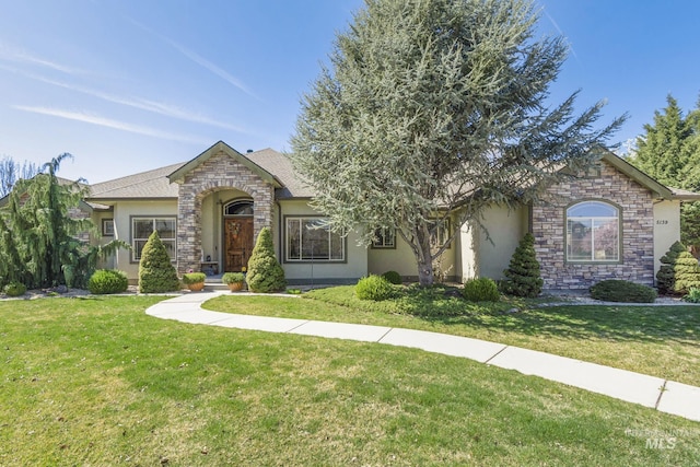 view of front of property featuring a front yard, stone siding, and stucco siding