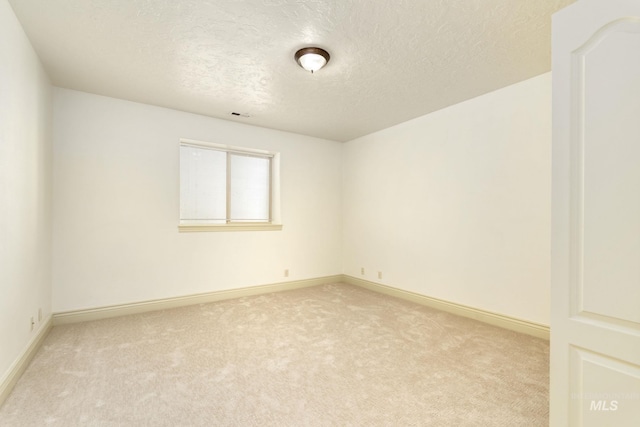 unfurnished room with a textured ceiling, light colored carpet, and baseboards