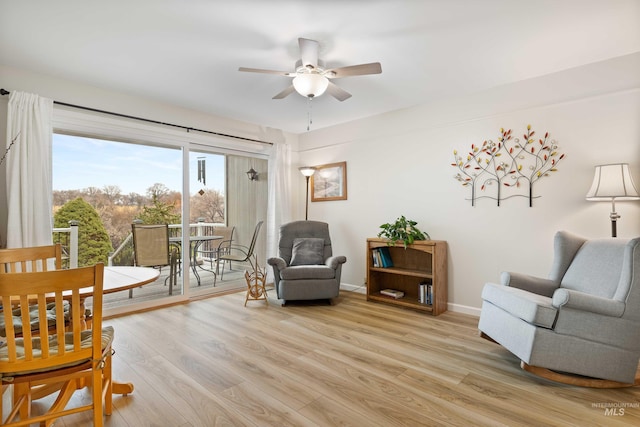 living area featuring light wood-style floors, baseboards, and a ceiling fan