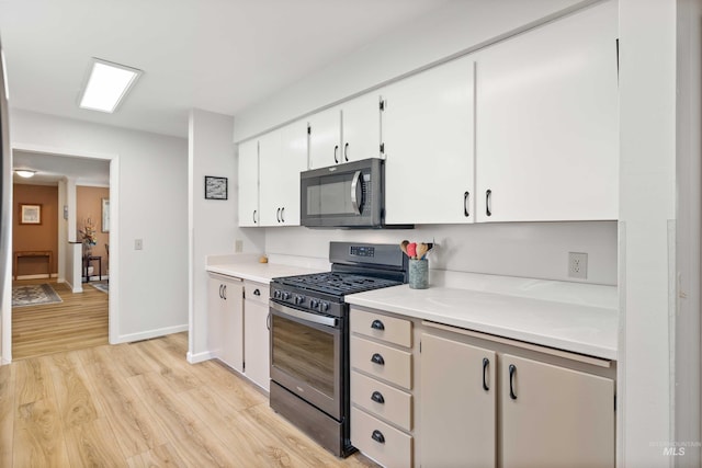 kitchen featuring stainless steel gas range oven, baseboards, white cabinets, light countertops, and light wood-type flooring