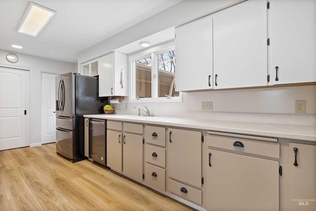 kitchen featuring stainless steel appliances, light wood-style flooring, a sink, and light countertops