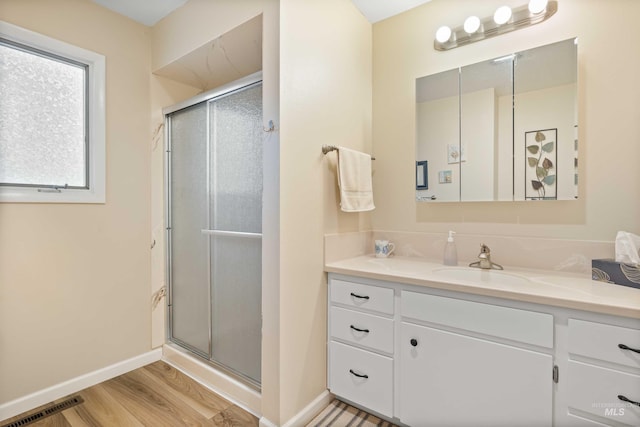 full bathroom featuring wood finished floors, a stall shower, vanity, and visible vents