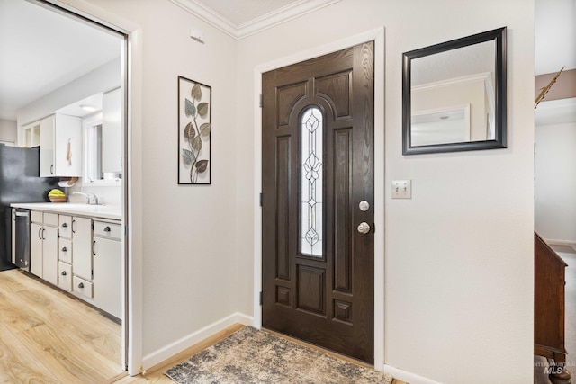 entryway with ornamental molding, light wood-type flooring, and baseboards