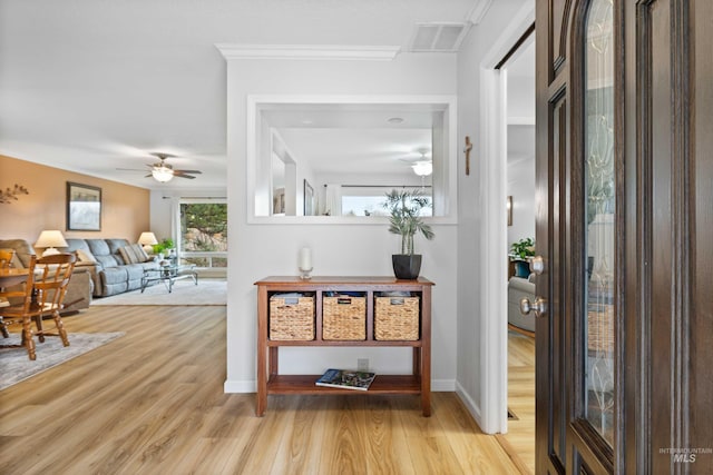 hallway with baseboards, visible vents, wood finished floors, and ornamental molding