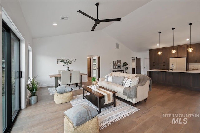 living area featuring ceiling fan, light wood finished floors, and visible vents