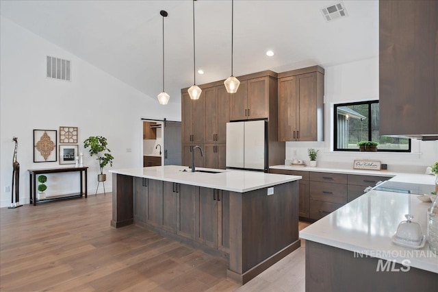 kitchen featuring a barn door, a sink, visible vents, light countertops, and freestanding refrigerator