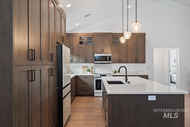 kitchen with light wood finished floors, visible vents, appliances with stainless steel finishes, vaulted ceiling, and a sink