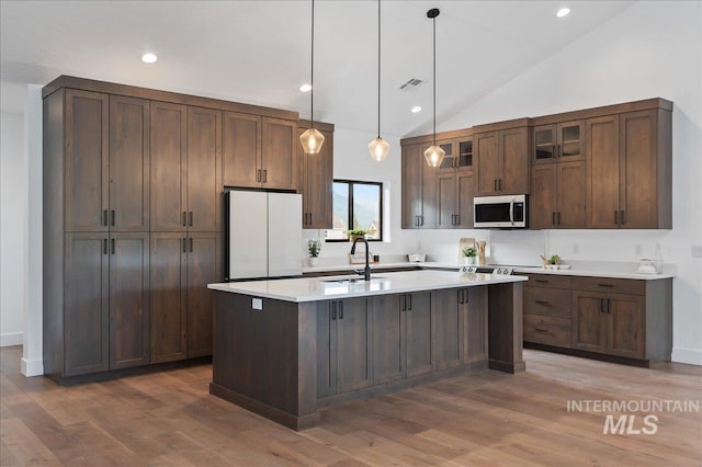 kitchen featuring a sink, visible vents, freestanding refrigerator, stainless steel microwave, and glass insert cabinets