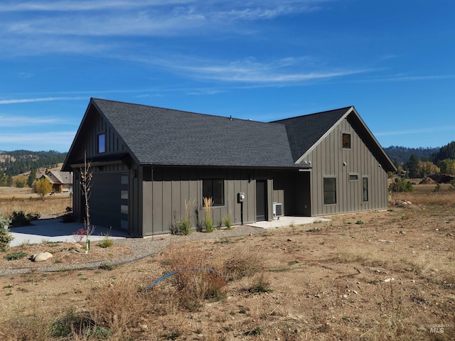 view of front facade with board and batten siding and a shingled roof