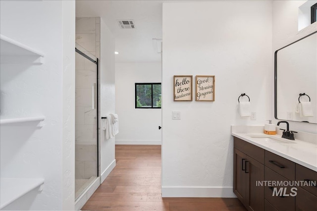 full bath featuring a stall shower, visible vents, vanity, and wood finished floors