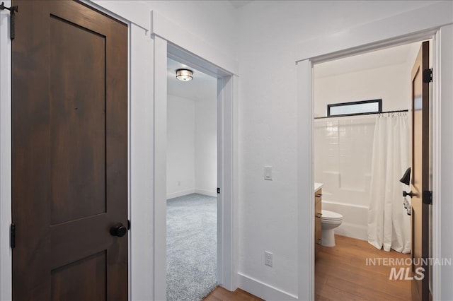 full bath with baseboards, wood finished floors, toilet, and shower / tub combo with curtain