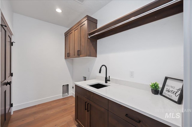 kitchen with recessed lighting, a sink, baseboards, light countertops, and light wood finished floors