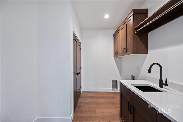 kitchen with light wood-style flooring, recessed lighting, a sink, baseboards, and light countertops