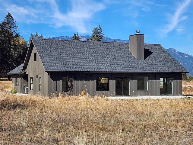 back of property featuring a shingled roof, a chimney, and a mountain view