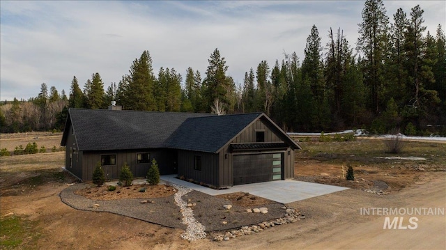 view of front of property with board and batten siding, concrete driveway, and a chimney