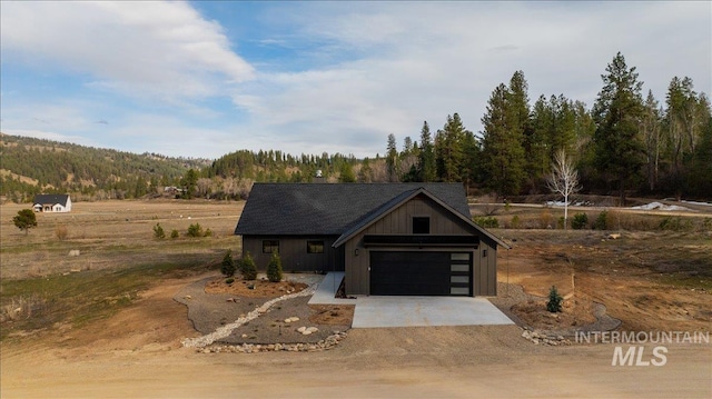 view of front facade featuring a garage, driveway, and a view of trees