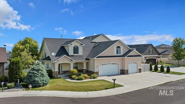 craftsman house with fence, a garage, driveway, stone siding, and a front lawn