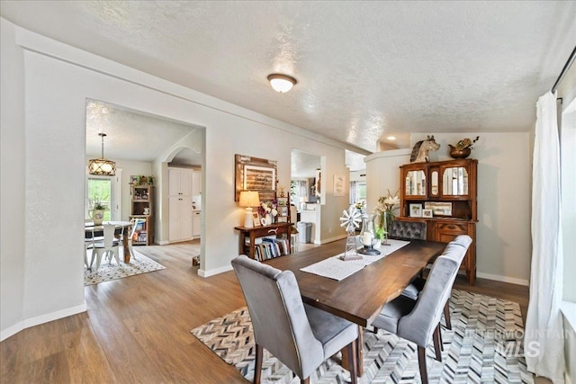 22969 Bumble Bee, Middleton, ID 83644 - dining area featuring a textured ceiling, light wood-style floors, baseboards, a chandelier, and arched walkways