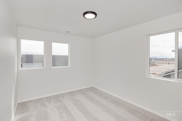 unfurnished room featuring plenty of natural light and light colored carpet