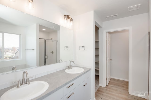 bathroom with hardwood / wood-style floors, vanity, and a shower with shower door