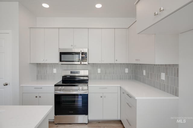 kitchen with white cabinets, appliances with stainless steel finishes, and light wood-type flooring