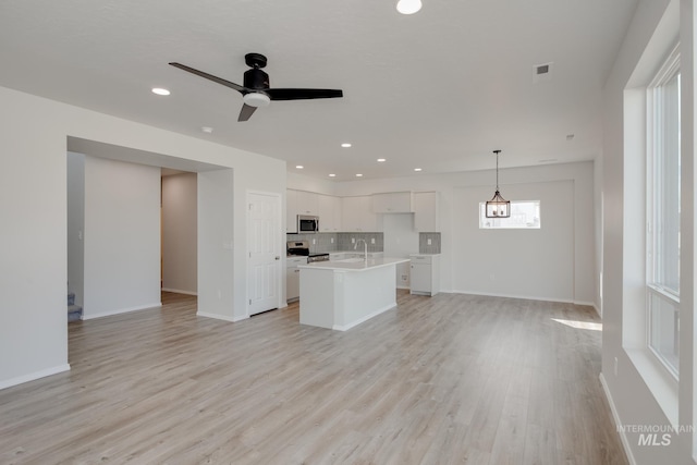 unfurnished living room featuring light hardwood / wood-style floors, ceiling fan, and sink