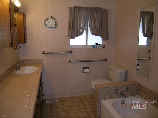 bathroom with vanity, a bath, and toilet