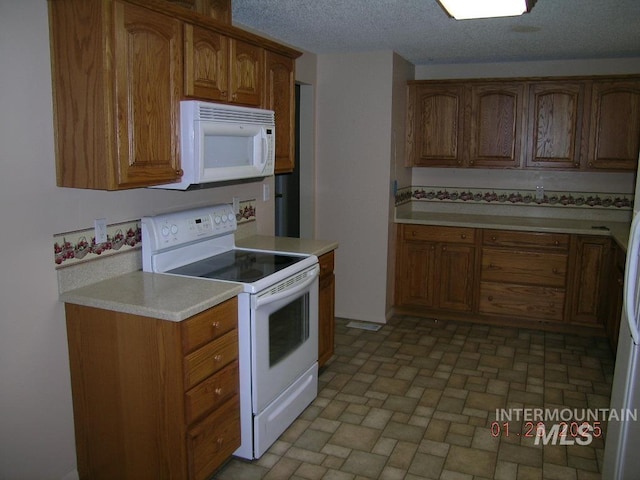 kitchen featuring a textured ceiling and white appliances