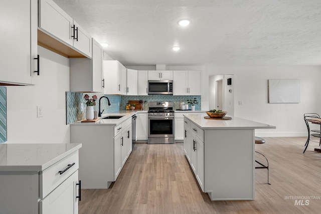 kitchen with a sink, stainless steel appliances, a kitchen breakfast bar, backsplash, and a center island