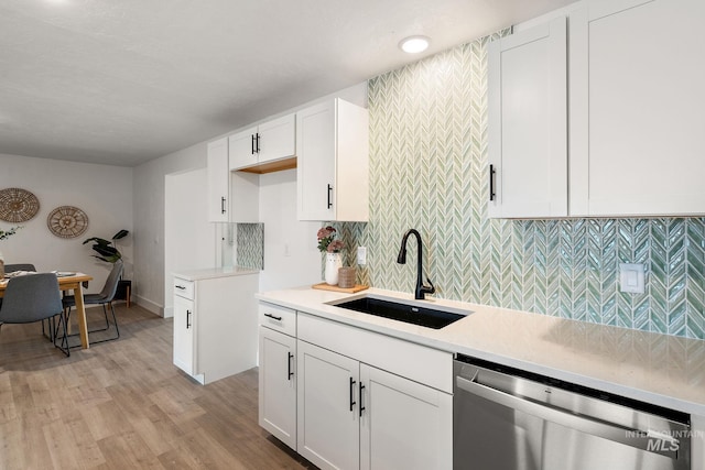 kitchen featuring a sink, stainless steel dishwasher, light wood-style floors, white cabinets, and light countertops