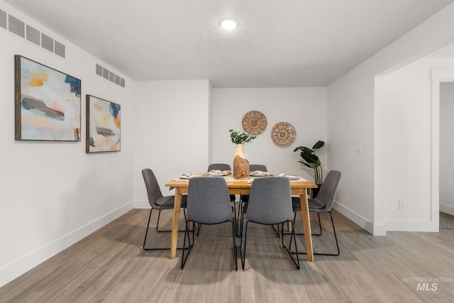 dining room featuring light wood-style floors, visible vents, and baseboards