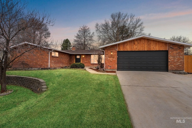 view of front of property featuring a yard, a chimney, concrete driveway, a garage, and brick siding