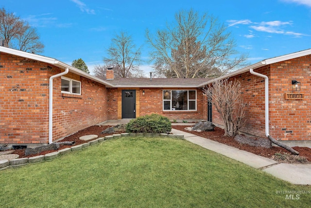 property entrance with a lawn, brick siding, and a chimney