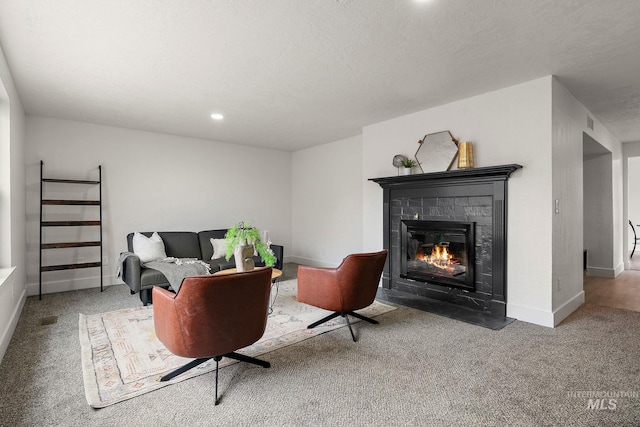 carpeted living room with recessed lighting, baseboards, a fireplace with flush hearth, and a textured ceiling