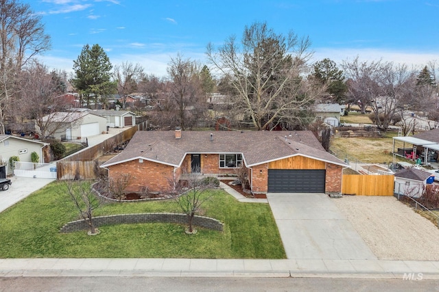 view of front of home featuring brick siding, concrete driveway, a front yard, and fence