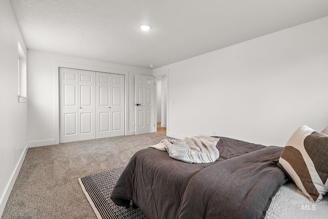 carpeted bedroom with a closet and baseboards