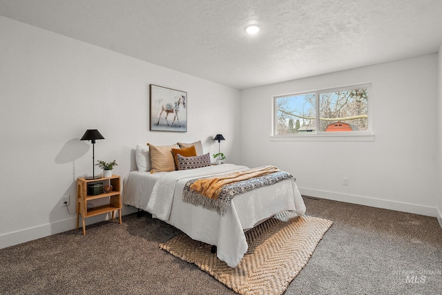 bedroom featuring dark colored carpet, baseboards, and a textured ceiling