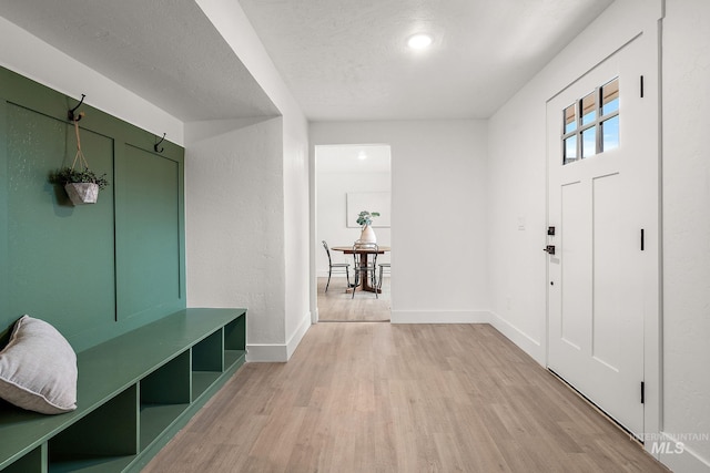 entryway featuring a textured ceiling, baseboards, and light wood-style floors