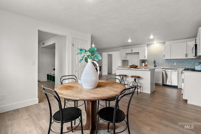 dining space featuring recessed lighting, a textured ceiling, baseboards, and light wood-style floors