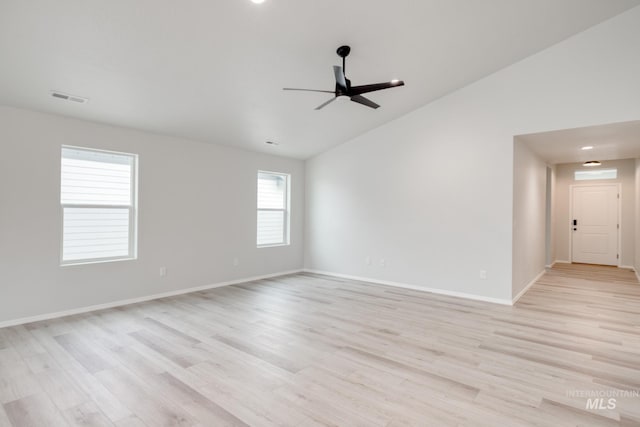 empty room featuring visible vents, light wood-style flooring, a ceiling fan, and vaulted ceiling