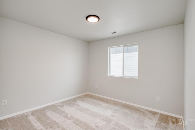 spare room featuring light carpet, visible vents, and baseboards