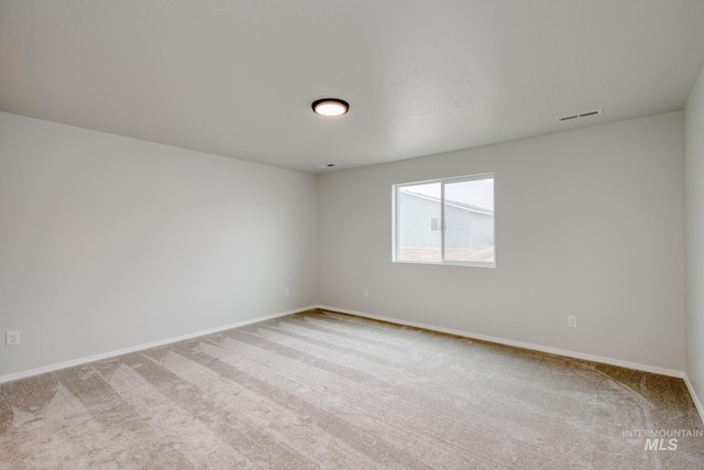 empty room featuring visible vents, baseboards, and carpet