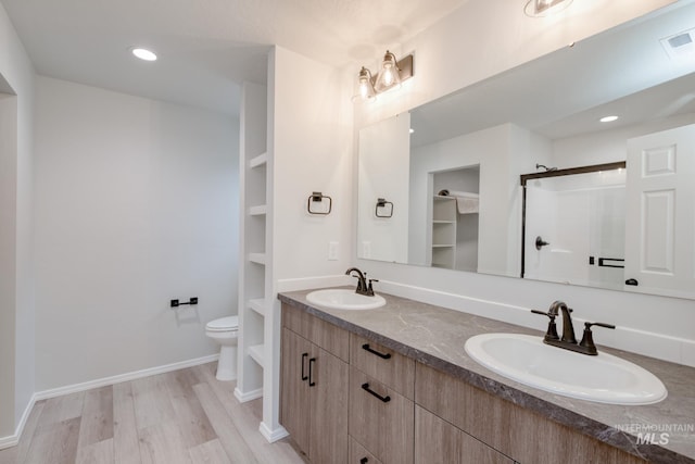 bathroom featuring a shower stall, toilet, wood finished floors, and a sink