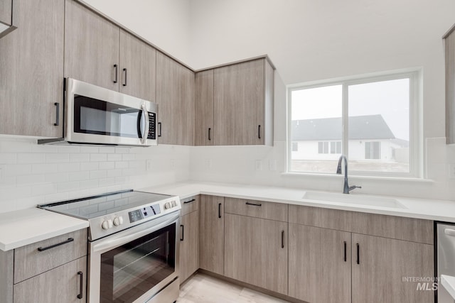 kitchen featuring light brown cabinetry, appliances with stainless steel finishes, and a sink