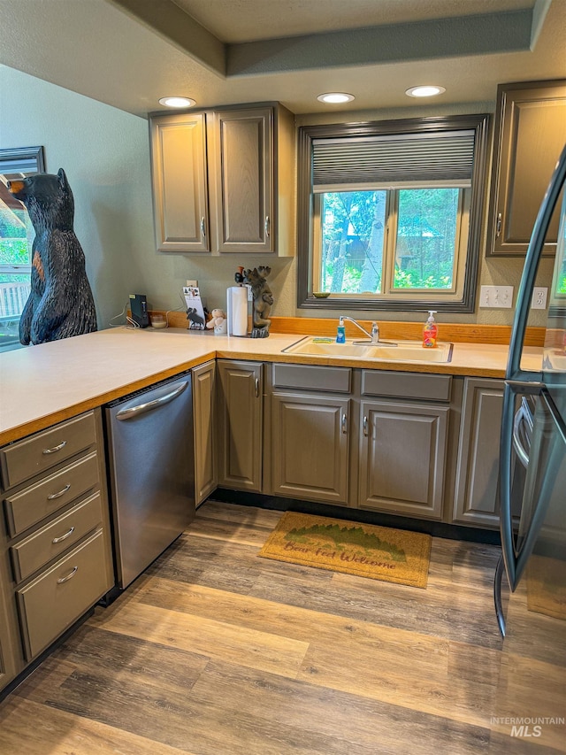 kitchen with sink, dishwasher, hardwood / wood-style flooring, and black fridge