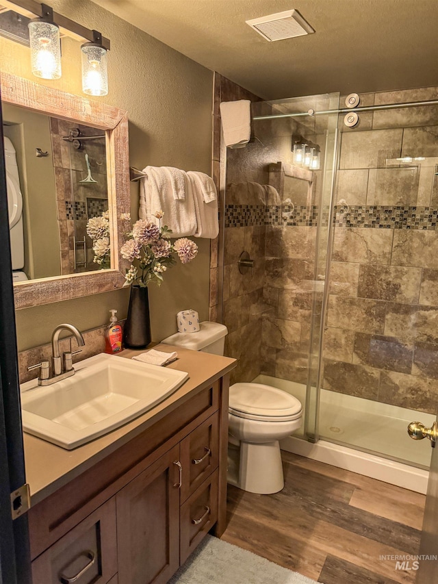 bathroom featuring a textured ceiling, an enclosed shower, toilet, vanity, and hardwood / wood-style floors