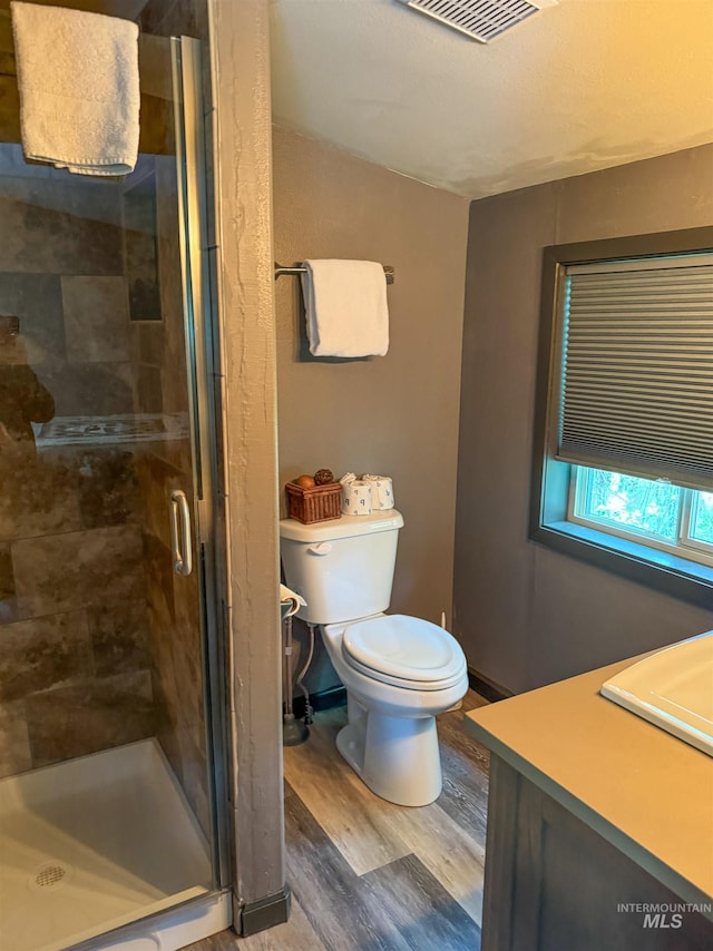 bathroom with vanity, toilet, a shower with door, and wood-type flooring