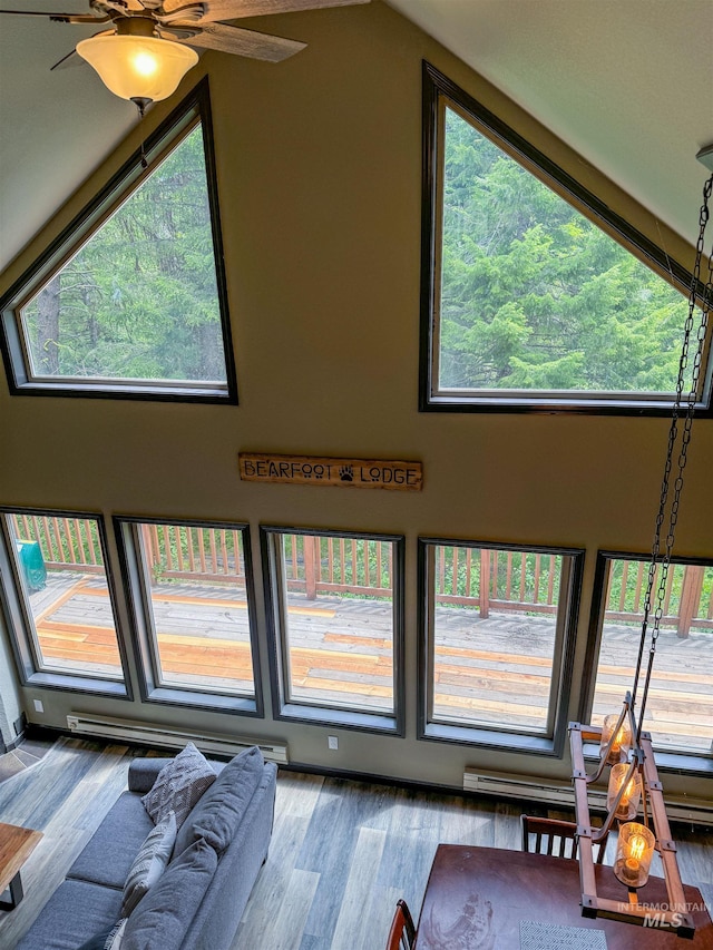 unfurnished living room with ceiling fan, hardwood / wood-style flooring, a healthy amount of sunlight, and a towering ceiling